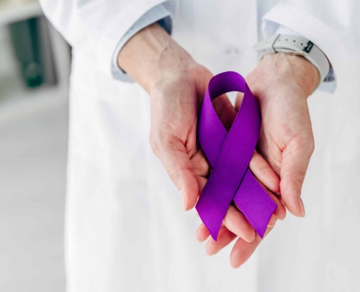 cropped view of doctor holding purple ribbon in clinic